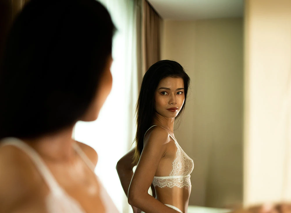 woman in white ligerie looking in mirror | Premier Cosmetic LA